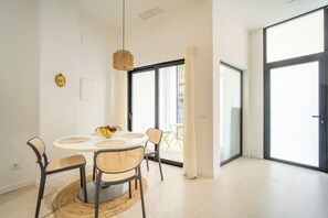 Un espace repas moderne avec une table ronde, des chaises en osier et un luminaire suspendu.