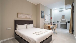Ein Hotelzimmer mit einem großen Bett, einem Schreibtisch und einer Küchenzeile.