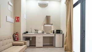 Eine kompakte Küchenzeile mit Mikrowelle, Toaster und Spüle. Ein Feuerlöscher ist an der Wand angebracht.