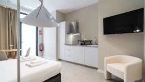 Une chambre d’hôtel équipée d’un lit, d’un bureau, d’une chaise, d’une kitchenette et d’un téléviseur.