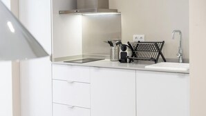 Une cuisine moderne avec des armoires blanches, une hotte de cuisinière en acier inoxydable, un évier et un porte-ustensiles noir.