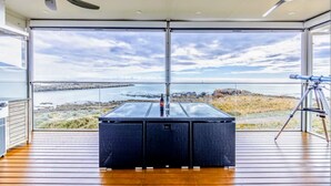 A room with a large window offering a view of the sea and rocky landscape.