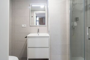 Une salle de bain moderne avec un meuble-lavabo blanc, un miroir et une cabine de douche en verre.