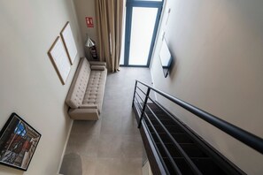 Un couloir avec un canapé, un extincteur et un panneau indiquant la sortie de secours.