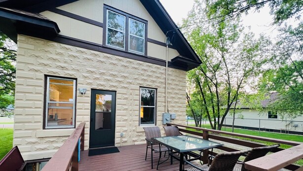 Ein Haus mit einer Steinaußenwand, einer Terrasse mit Gartenmöbeln und einer schwarzen Tür.