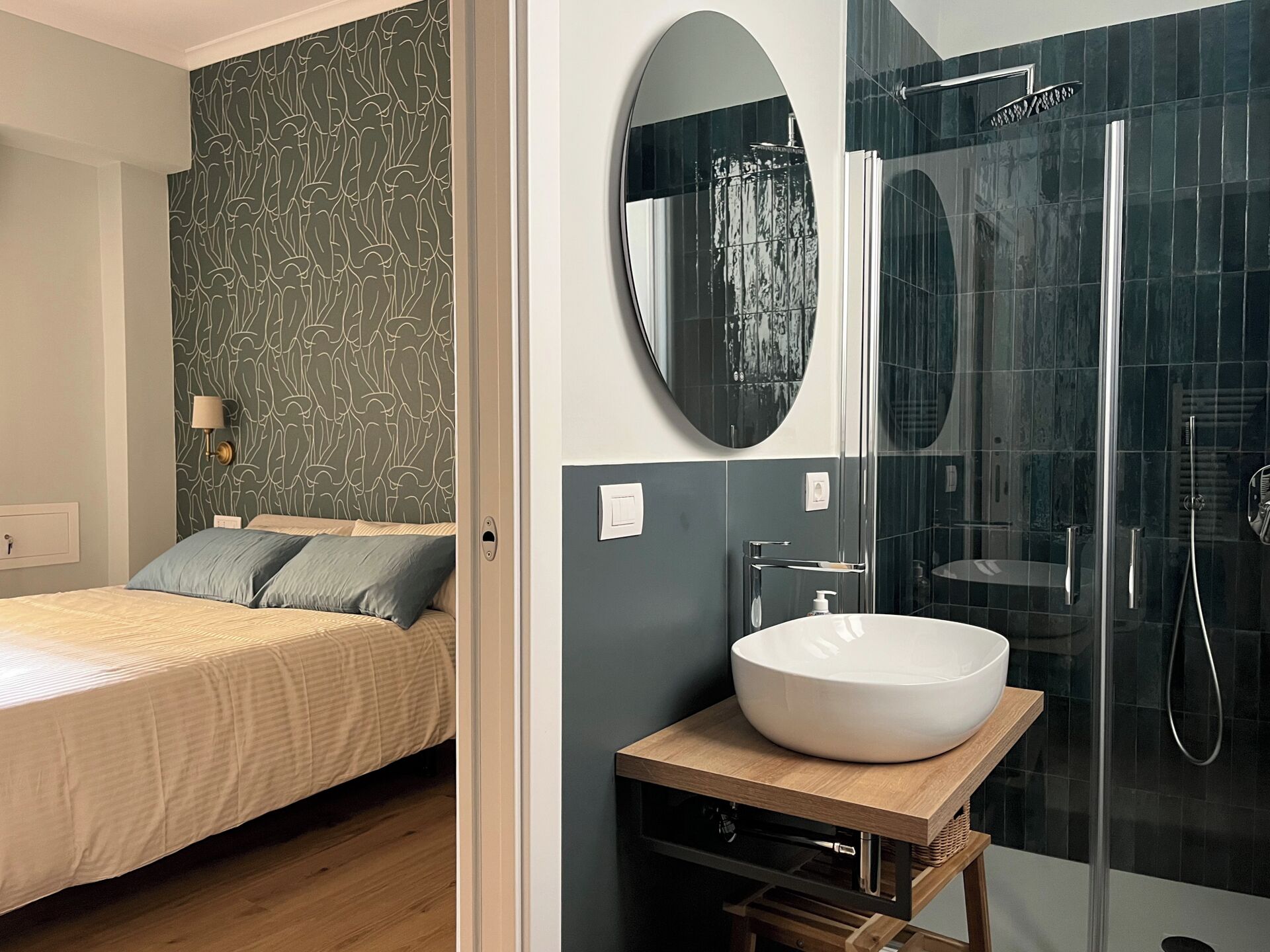 A modern bedroom with a bed, a bedside table, and a nightstand. The bathroom features a large mirror, a sink, and a shower.