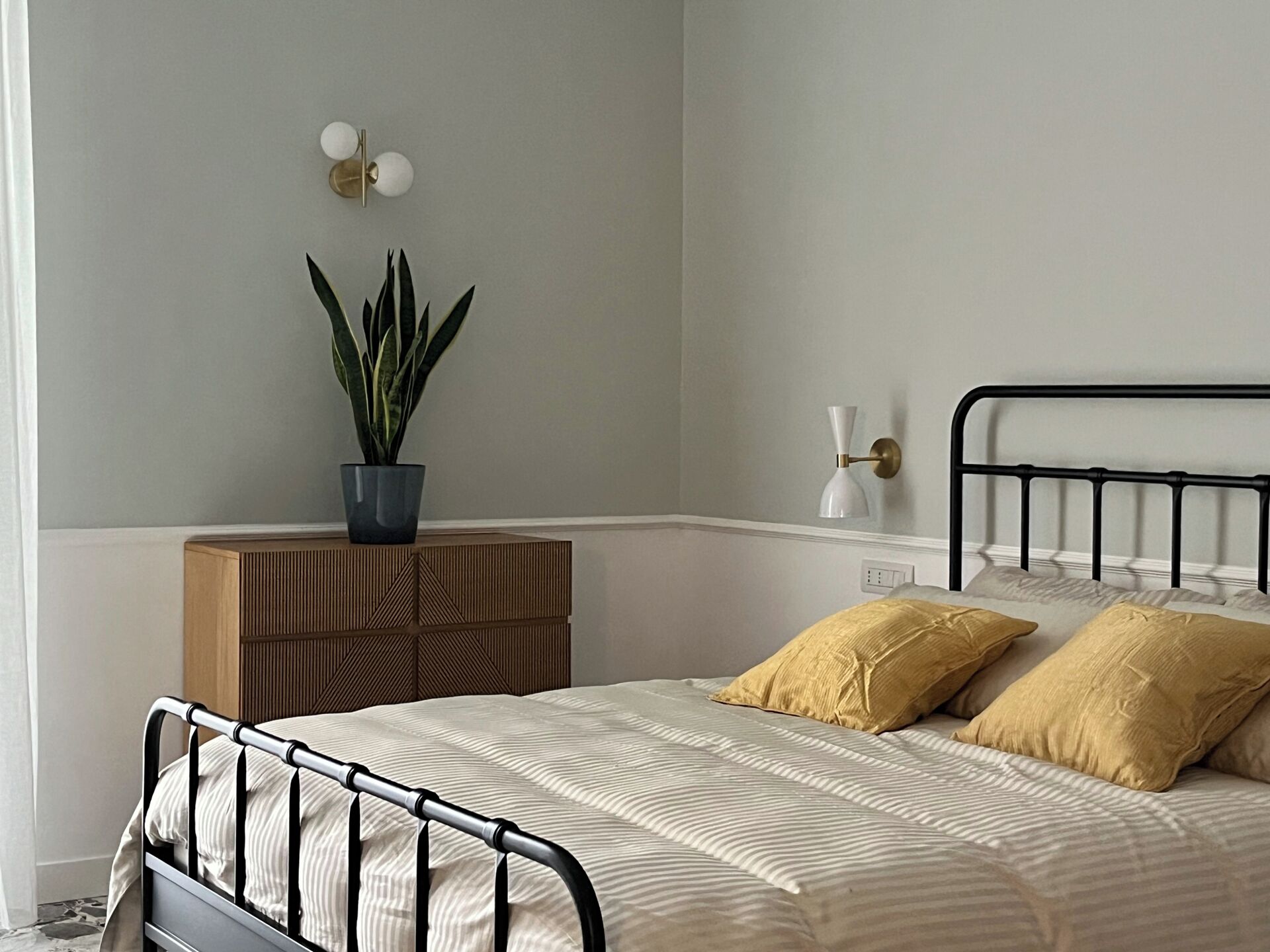 Ein ordentlich eingerichtetes Schlafzimmer mit Bett, Nachttisch, Lampe und einem Blumentopf.