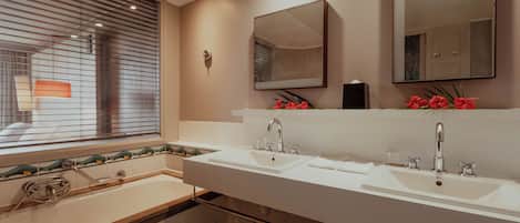 A bathroom with a double sink, a large mirror, and a window with blinds.
