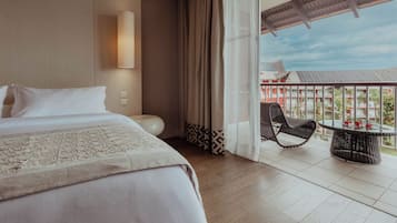 A hotel room with a bed, a round table, a chair, and a balcony with a view.