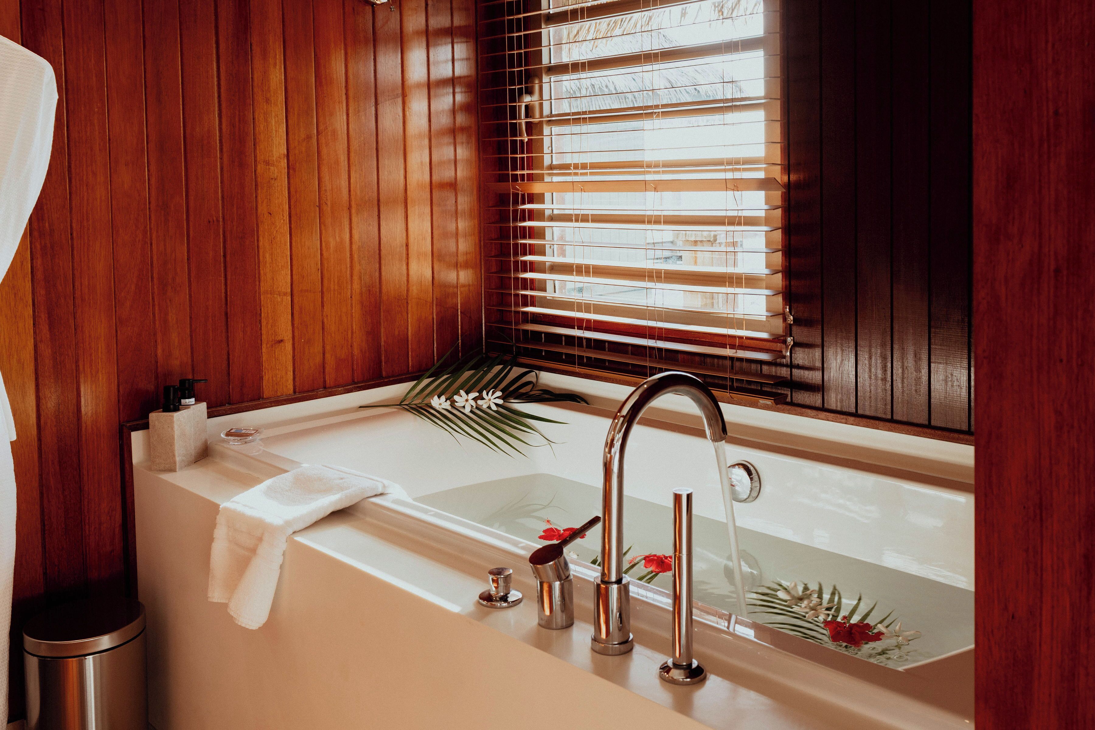 A bathroom with a bathtub, a sink, and wooden walls.
