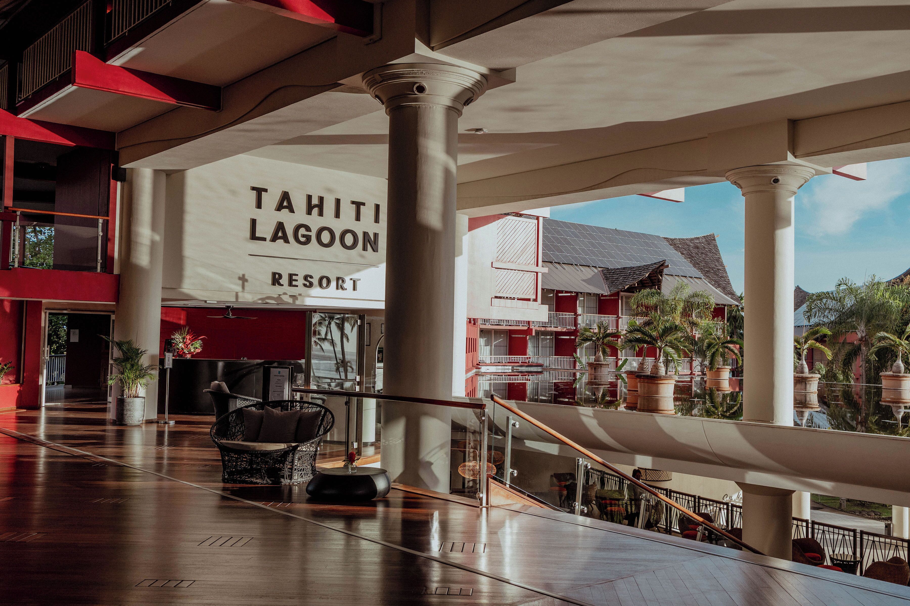 Eine geräumige Lobby mit einem Schild für das Tahiti Lagoon Resort, einem modernen Stuhl und Blick auf die Architektur des Resorts.