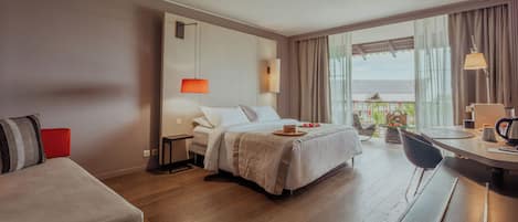 A hotel room with a bed, a desk, a chair, and a balcony with a view.