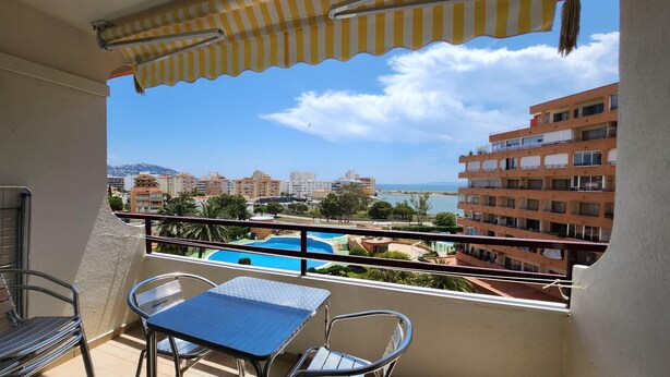 Ein Balkon mit Blick auf ein Schwimmbad, einem Tisch und Stühlen.
