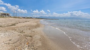 A beach with a sandy shore, a few buildings in the background, and a clear blue sky. - Stunning View, A Pool, Beach Access - Book Now! (Portmore)