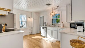 Una cocina moderna con armarios blancos, encimera de madera y lavavajillas integrado.