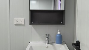 A bathroom with a white sink, a mirror, and a blue soap dispenser.