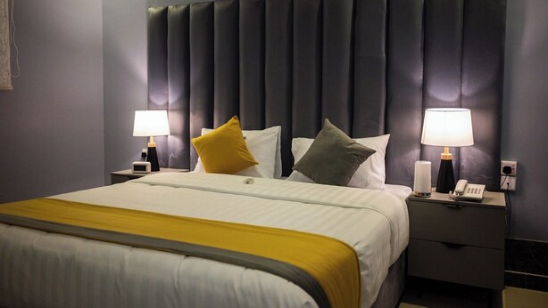 A hotel room with a large bed, two bedside tables, a nightstand, and a headboard. - Mawed Al Dyafa Serviced Apartments  (Riyadh)