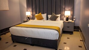 A hotel room with a large bed, two bedside tables with lamps, a padded headboard, and a marble-tiled floor. - Mawed Al Dyafa Serviced Apartments  (Riyadh)