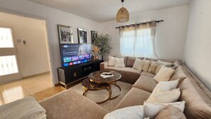 A living room with a sofa, a coffee table, a TV, and a plant. - Ibiza Sunshine Hideaway (Can Besso)