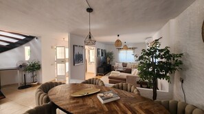 Uma sala de estar moderna com uma mesa de jantar de madeira, sofás confortáveis e uma grande planta em vaso.