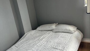 A single bed with a patterned white duvet in a room with grey walls and a wooden floor. - 6 Guests - 3 Bedrooms - Close to London Center (London)