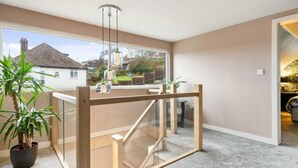 Un interior moderno con un separador de vidrio, una escalera y vistas al exterior.