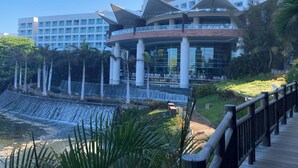 A modern hotel with a central atrium, a waterfall feature, and a wooden boardwalk.