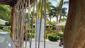 A row of wooden swings with ropes, a white car, and palm trees in the background.
