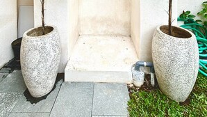 Eingang zum Spa mit einem steinernen Bogen, zwei großen Kübelpflanzen und einer kleinen Stufe zum Eingang.