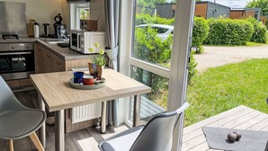 A modern kitchen with a dining area, large windows, and a view of a garden and parked car. - Lovely apartment in villa for 4 people with WIFI, TV and pets allowed (Beilngries)