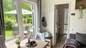 A modern living room with a dining area, large windows, and a view of a garden. - Lovely apartment in villa for 4 people with WIFI, TV and pets allowed (Beilngries)