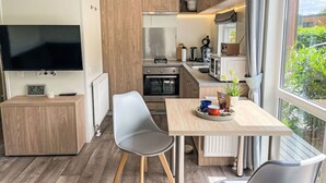 A compact kitchen with a TV, a dining area with a table and chairs, and a window with a view of greenery. - Lovely apartment in villa for 4 people with WIFI, TV and pets allowed (Beilngries)