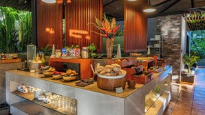 Un área de bufé con diversos alimentos, una estación de café y una planta decorativa como centro de mesa.