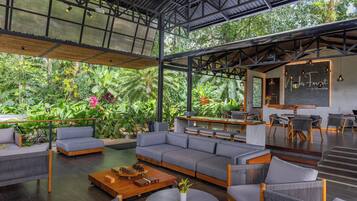 Un espace de vie moderne et ouvert, comprenant un grand canapé, des fauteuils, une table basse et un coin repas avec une table et des chaises.