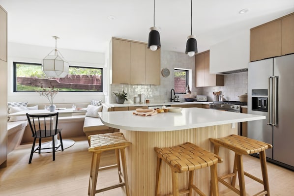 A modern kitchen with a large island, wooden bar stools, and a view of the outdoors. - Brand-New Vail 2BR Condo. Bright, Peaceful Retreat (Vail)