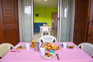 Ein Essbereich mit einem für das Frühstück gedeckten Tisch, darunter Teller mit Speisen, Tassen und eine Karaffe.