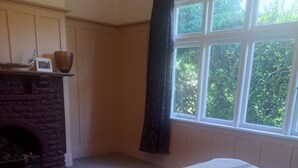 Un dormitorio con una cama grande, una chimenea y un ventanal con cortinas.