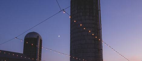 Two large cylindrical silos with string lights between them.