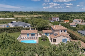 Zona residencial com casas, piscina e uma árvore em primeiro plano.