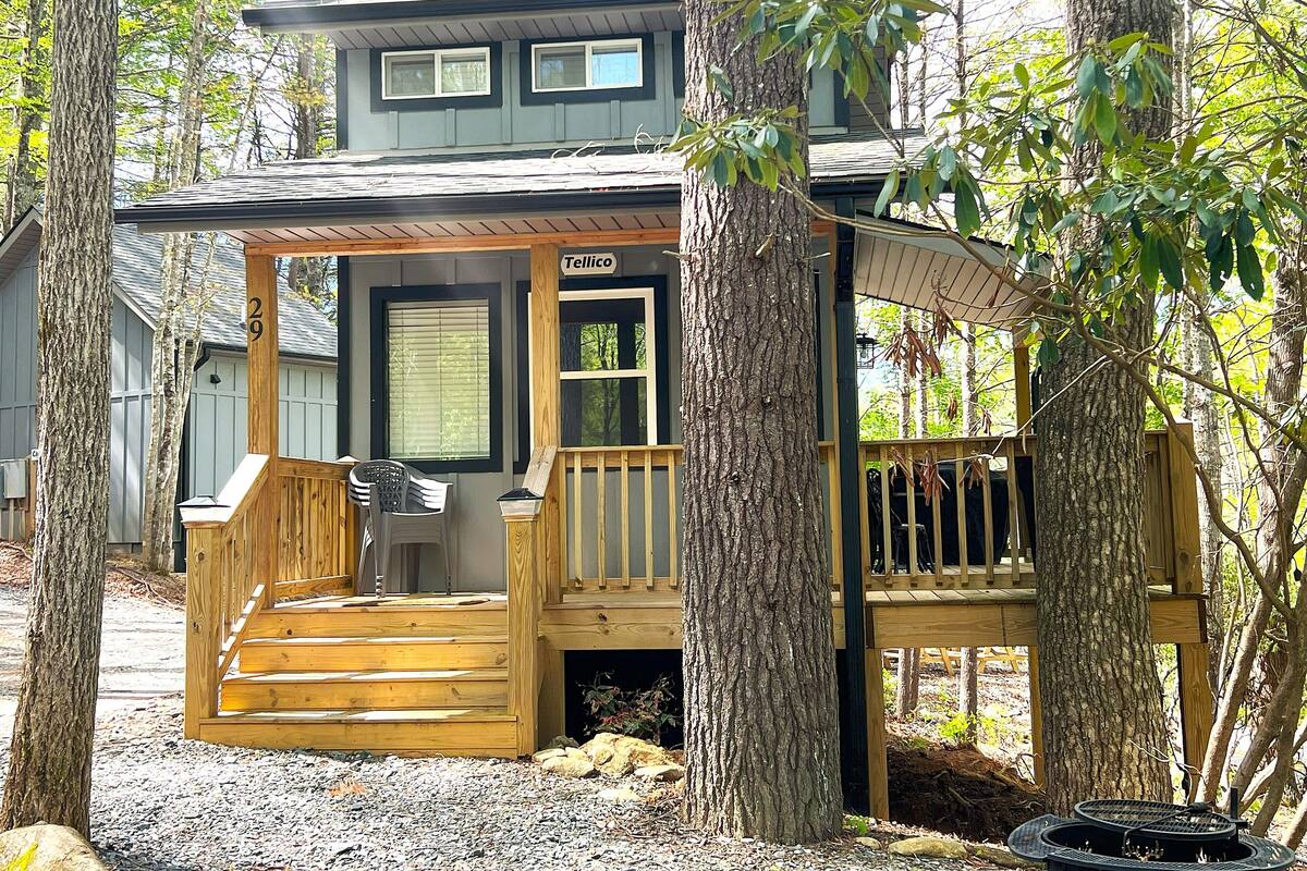 A cabin with a wooden deck, a porch, and a sign reading "Tellico".