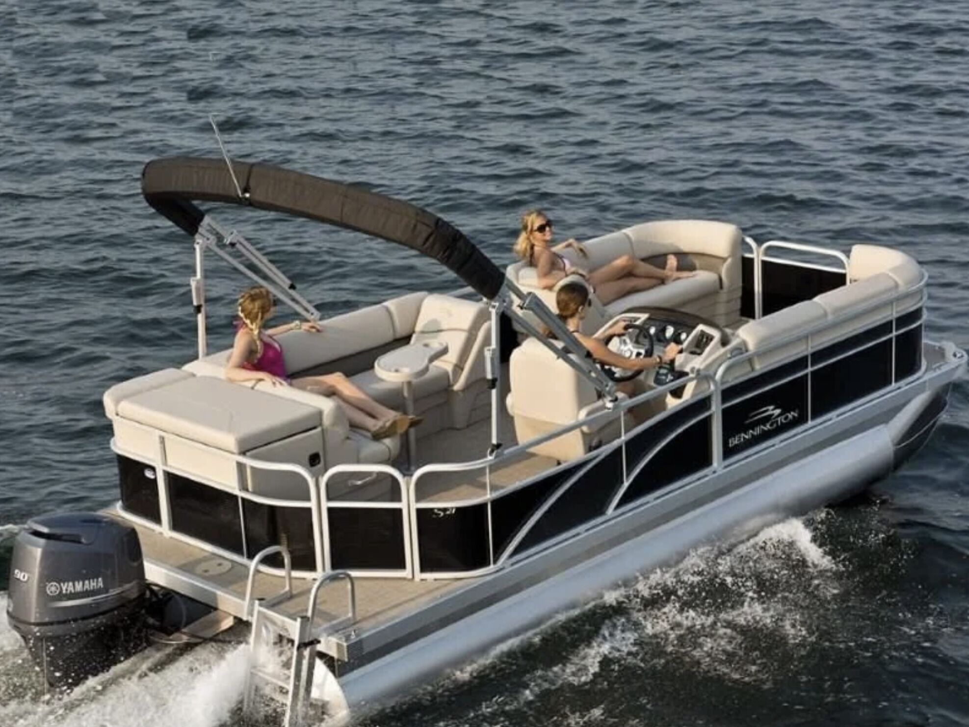 A motorboat with a covered seating area, a steering wheel, and a Yamaha outboard motor.