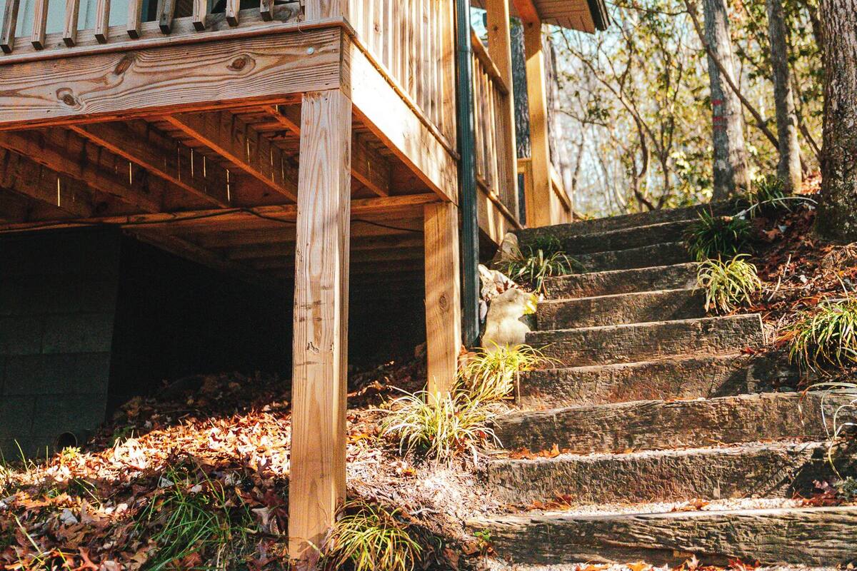 A wooden deck with a railing, a staircase leading to a house, and a number '22' on the house.