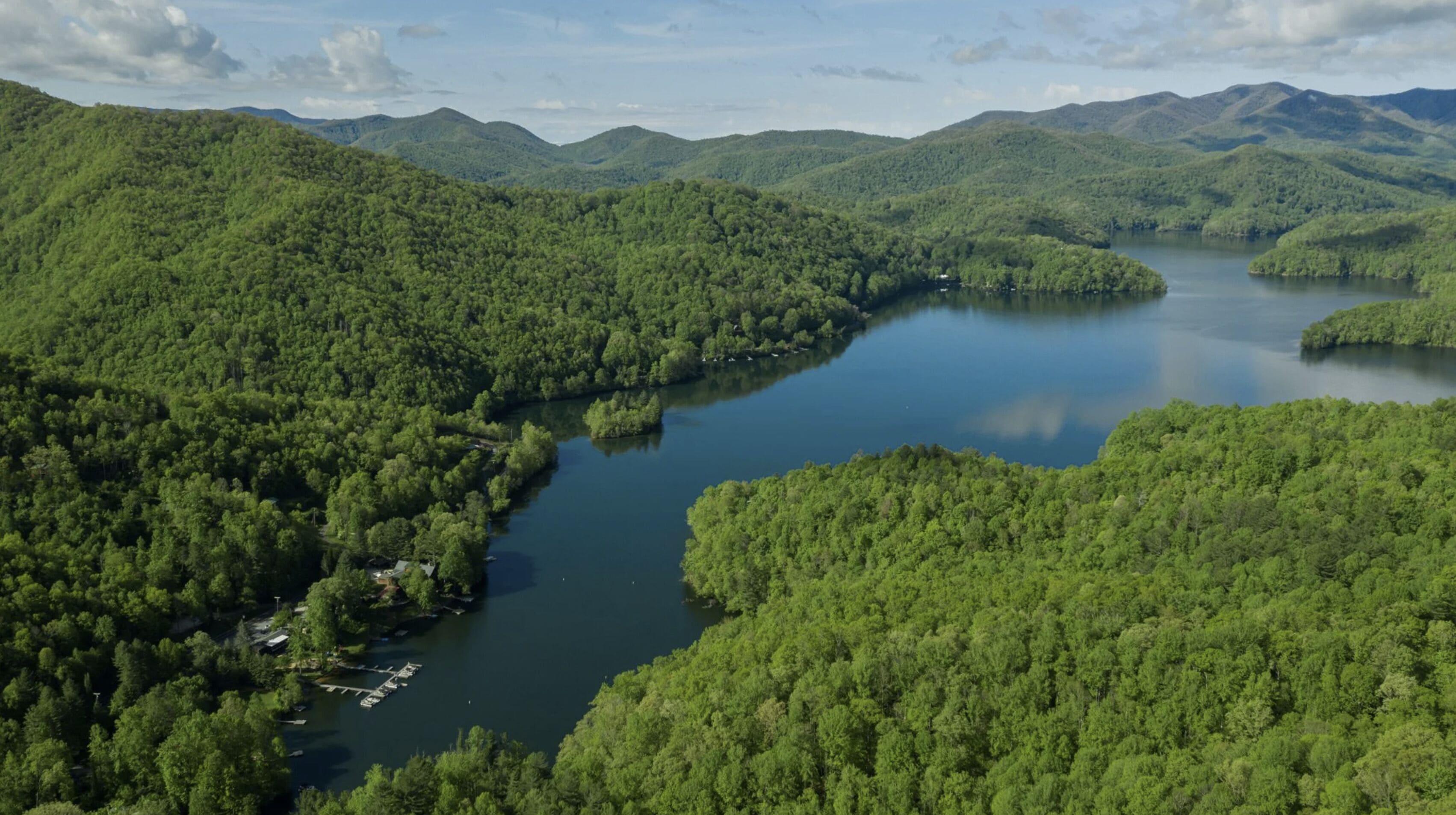 Un lago circondato da una fitta foresta e montagne.