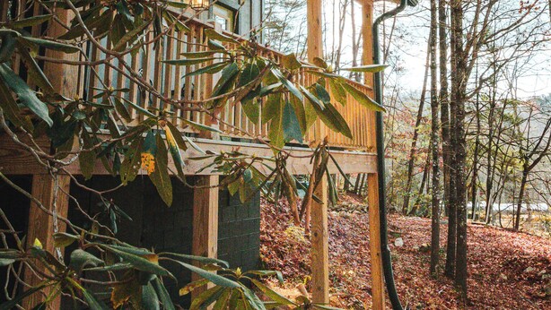 A house with a wooden porch and a view of the surrounding forest. - Wayah Ridge Escapes (Topton)