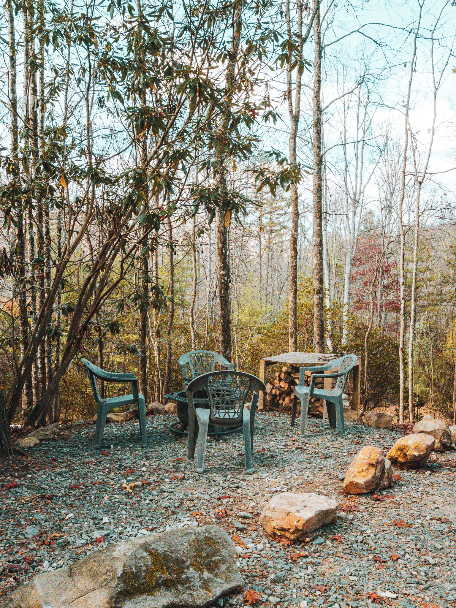 A forested area with a table and three chairs.
