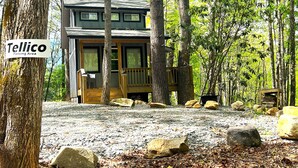 Eine Holzhütte mit Veranda, umgeben von Bäumen und Felsen.