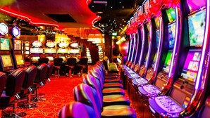 A row of slot machines in a casino with a red carpet and a curved ceiling design. - Wayah Ridge Escapes (Topton)
