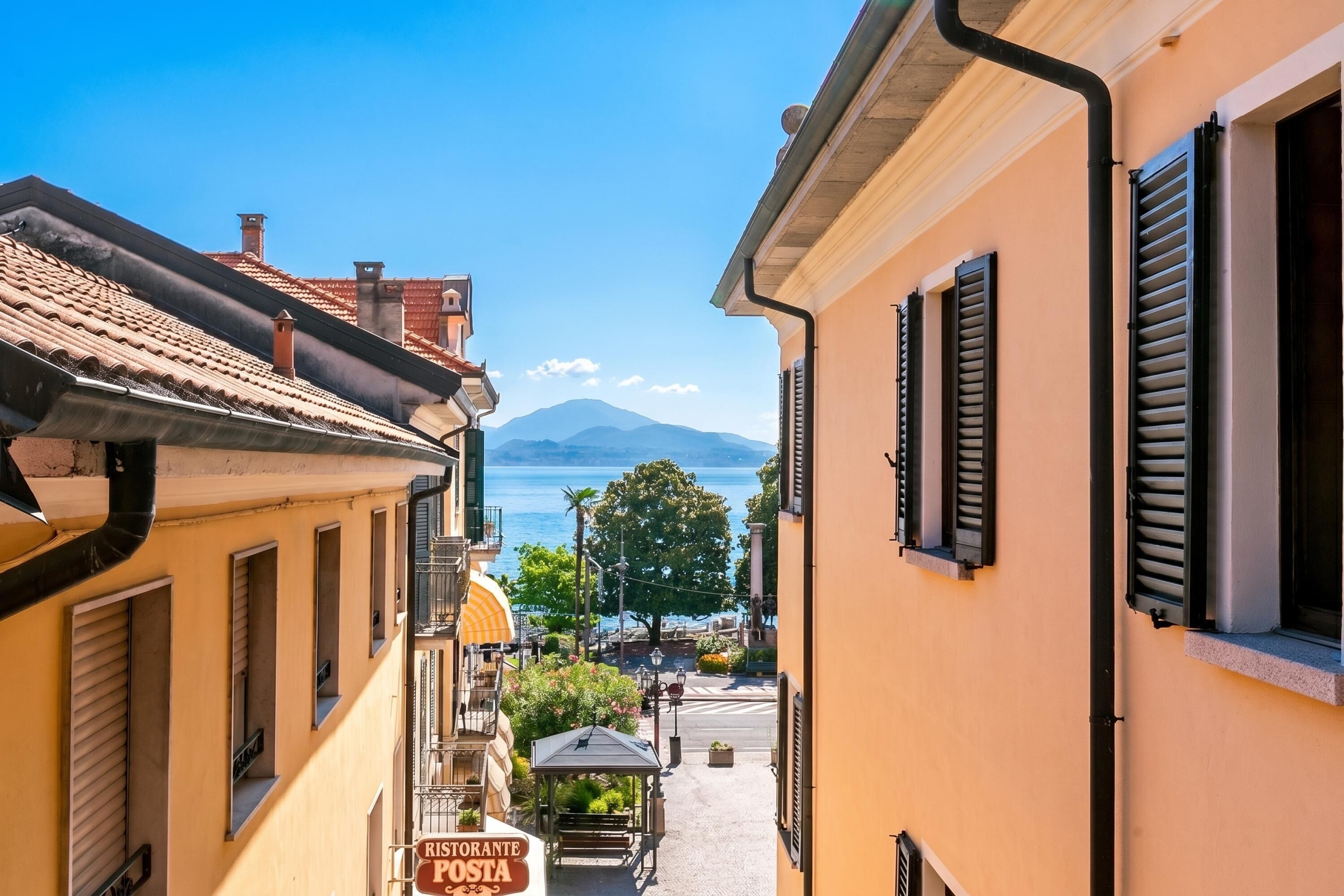 A narrow street with buildings, a restaurant sign, and a mountain in the background.