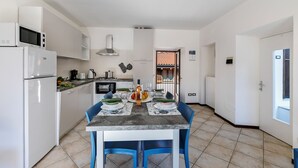 A modern kitchen with white cabinets, a built-in microwave, and a dining table set for four. - Nel Cuore Di Baveno Apartment, 50m from Lake, Baveno, Italy (Baveno)