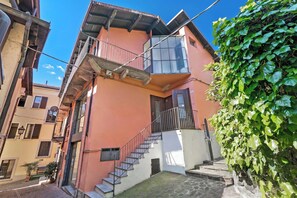 Un edificio de varios pisos con una escalera que lleva a un balcón, rodeado de vegetación.